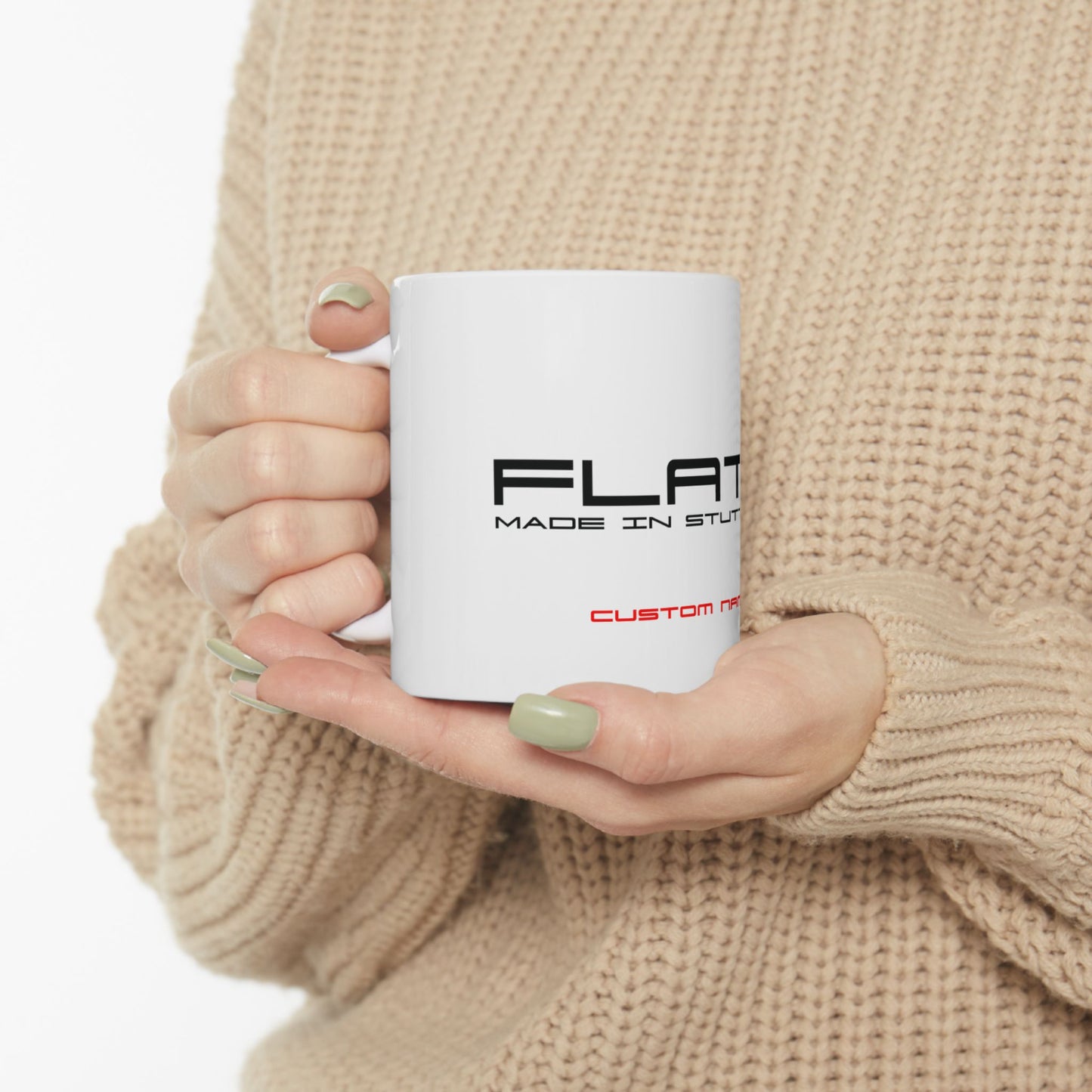 Person holding a white mug with text in a beige sweater