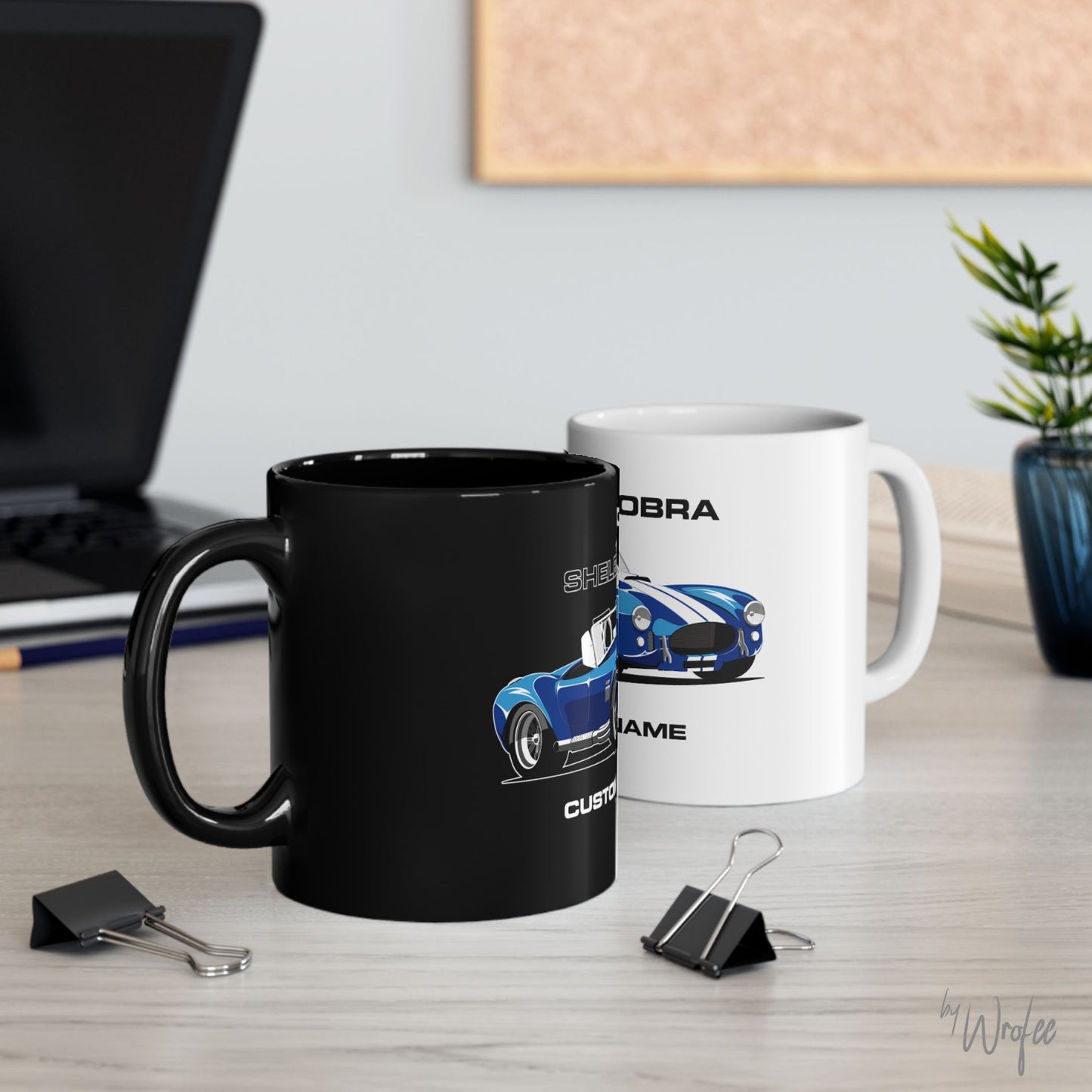 Two mugs with car designs on a desk with office supplies.