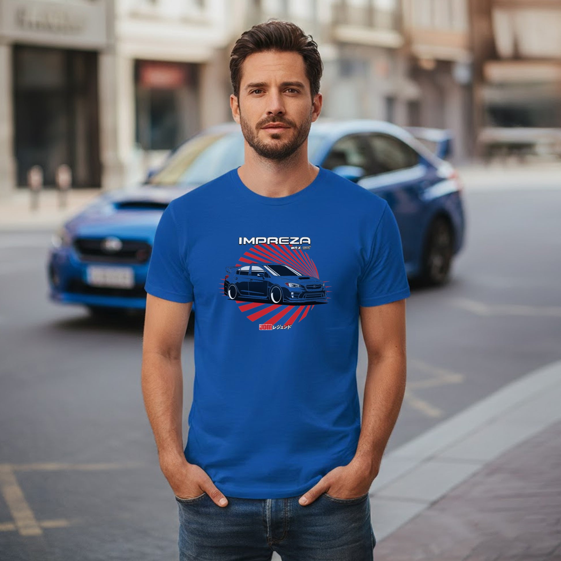 Man wearing a blue t-shirt with a car graphic and 'Impreza' text, standing on a street with a blue car in the background.