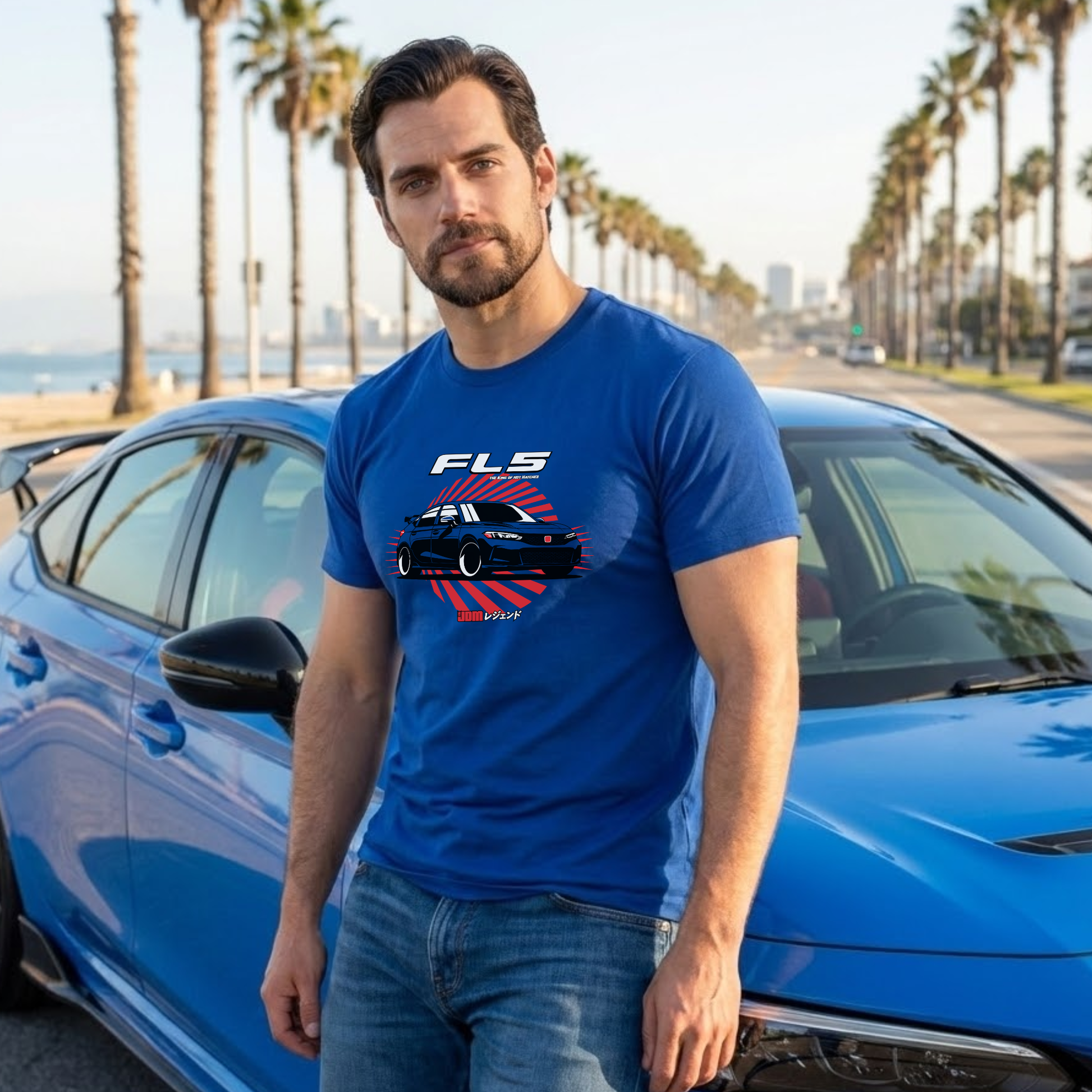 Man wearing a blue t-shirt with a car graphic and text, standing next to a blue car on a sunny day.