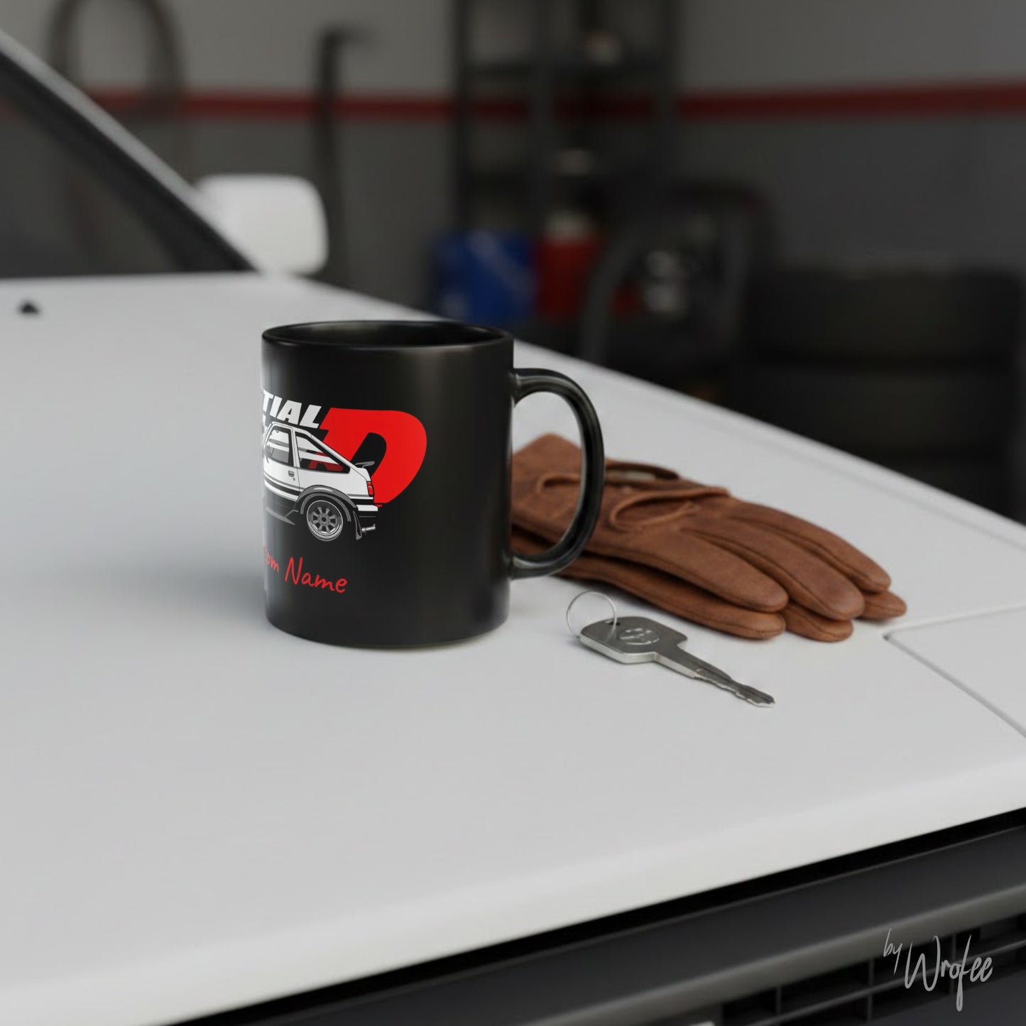 Black mug with car design, brown gloves, and key on a car hood