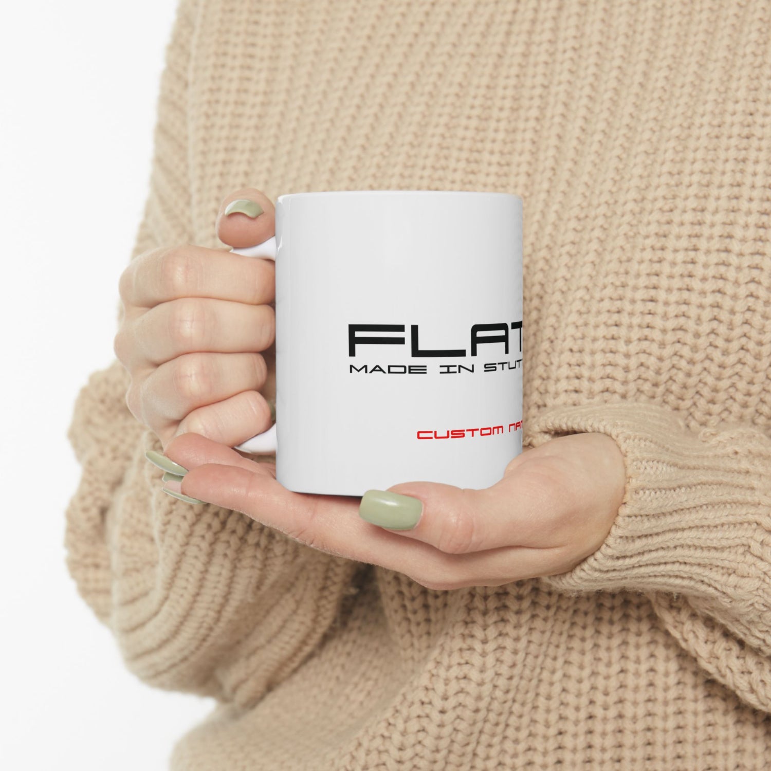 Person holding a white mug with text in a beige sweater